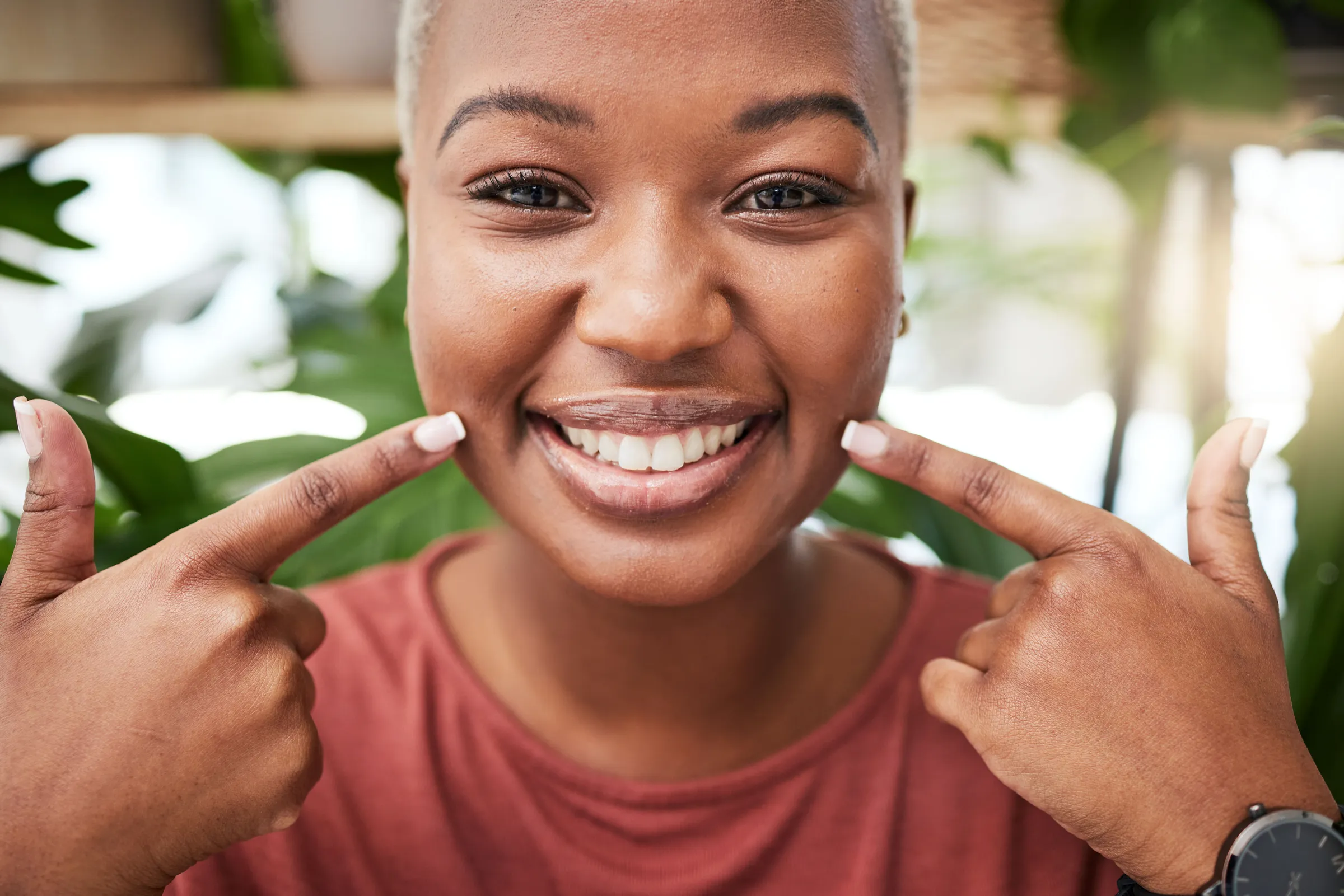 Smiling woman pointing at her front teeth with both index fingers