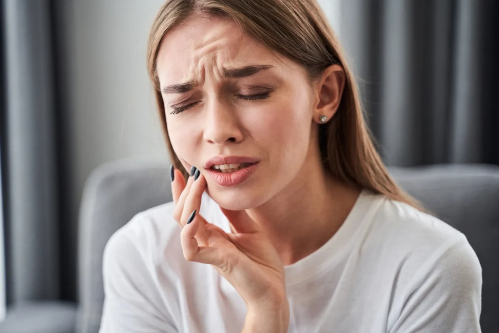 Woman holding her cheek with a pained expression