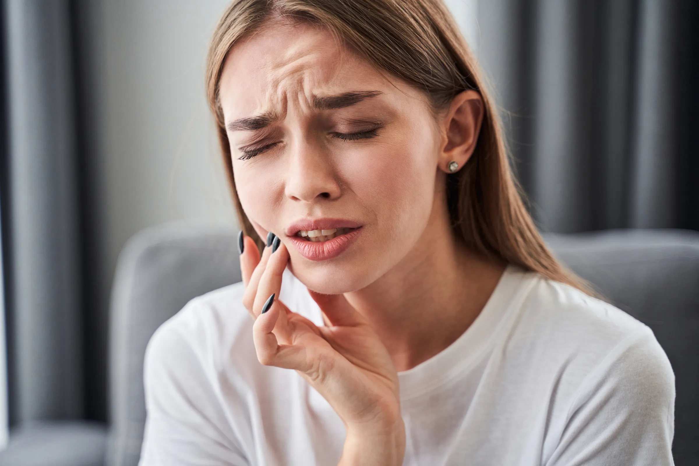 Woman holding her cheek with a pained expression