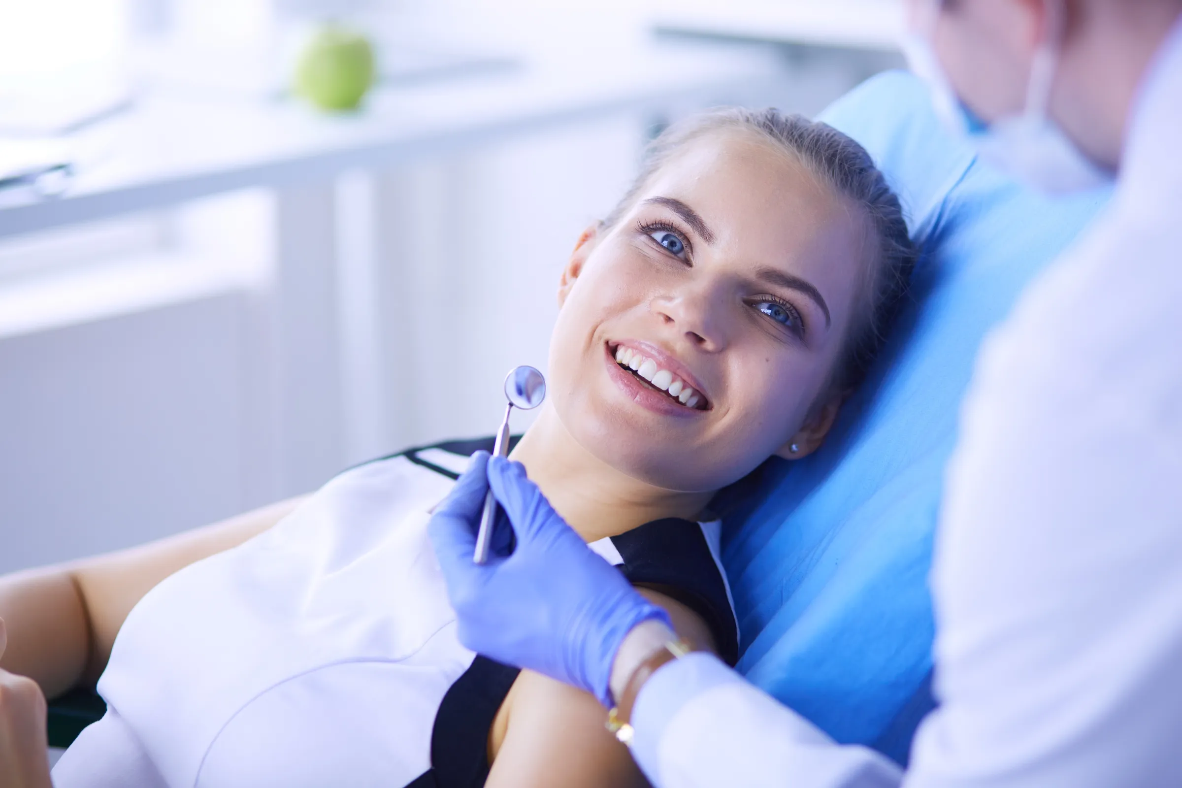 Woman in a dental chair while a dentist examines her teeth