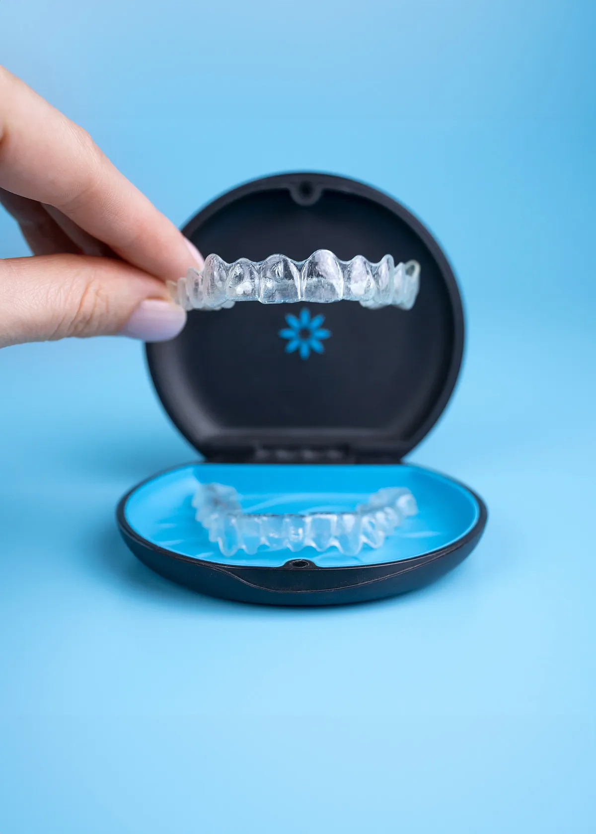 Hand lifting a clear aligner from its storage case