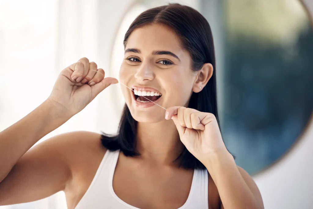 Smiling woman flossing her teeth