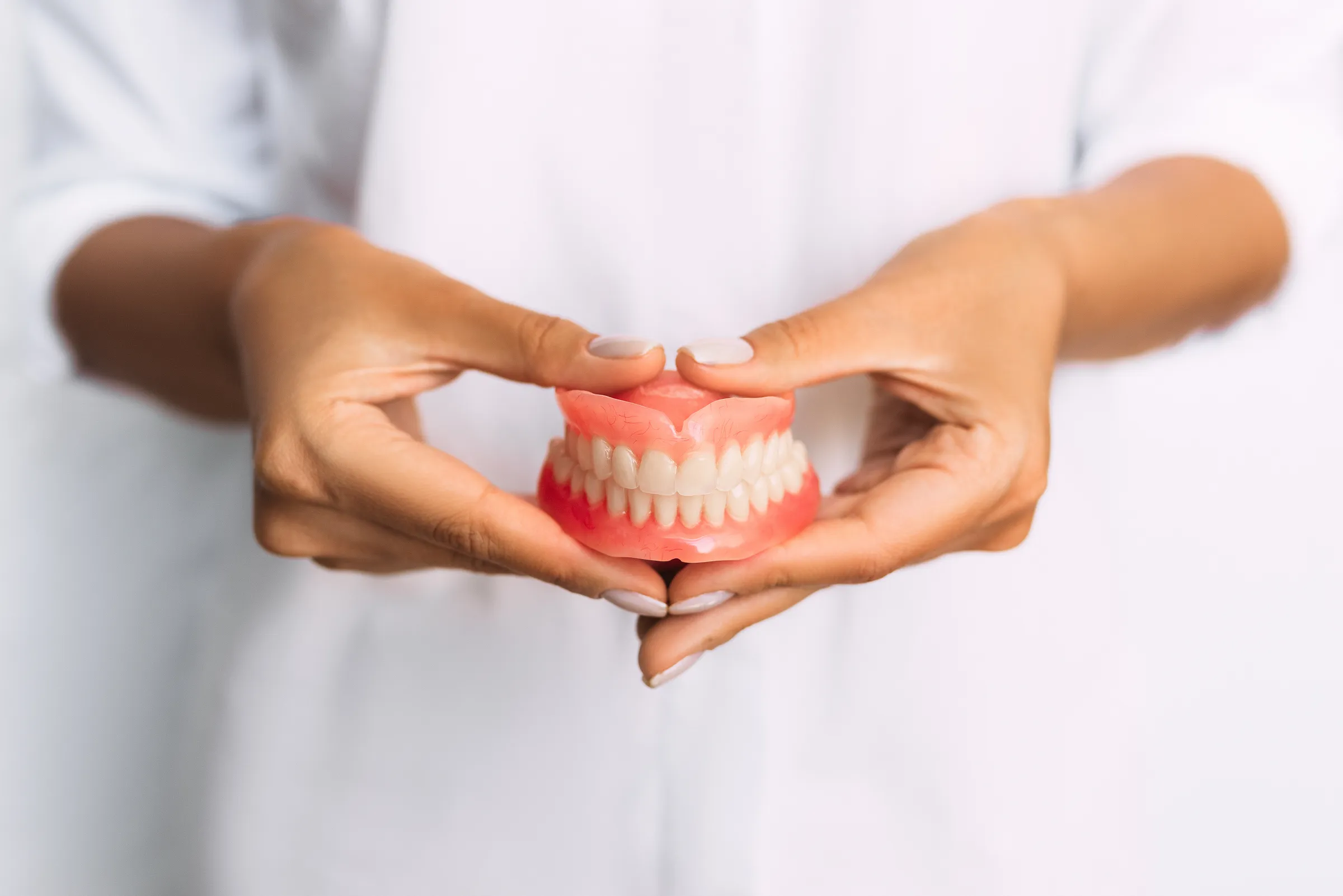 Clinician holding a full upper and lower denture