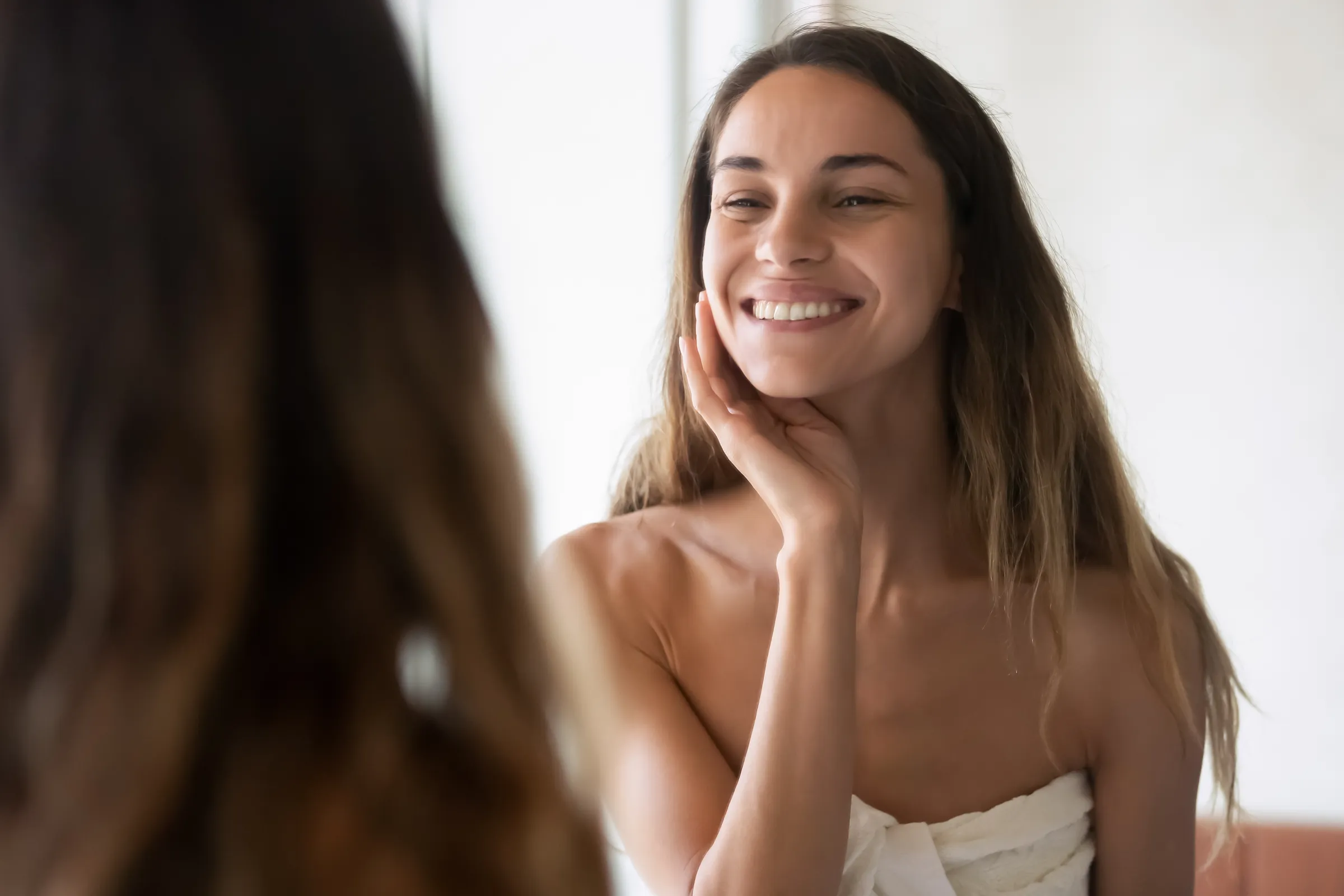 Woman smiling at her reflection in a mirror