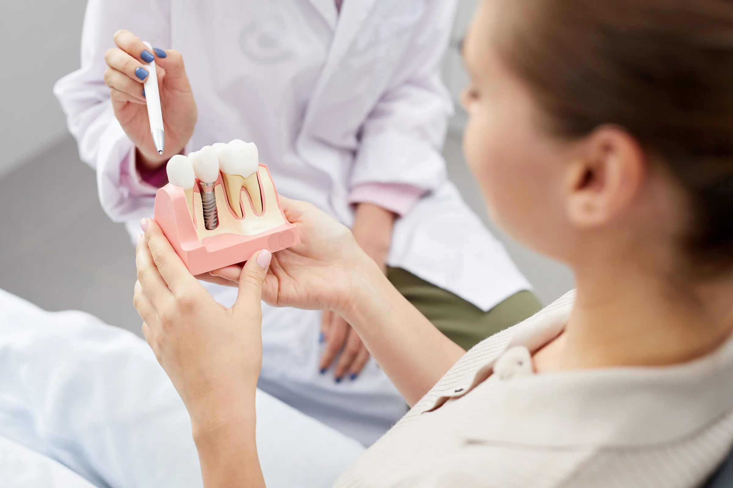 Dentist showing a patient a dental implant model