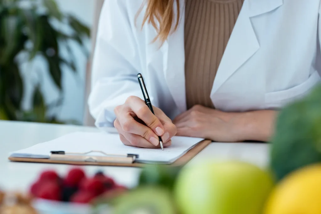Clinician writing notes beside fresh fruit