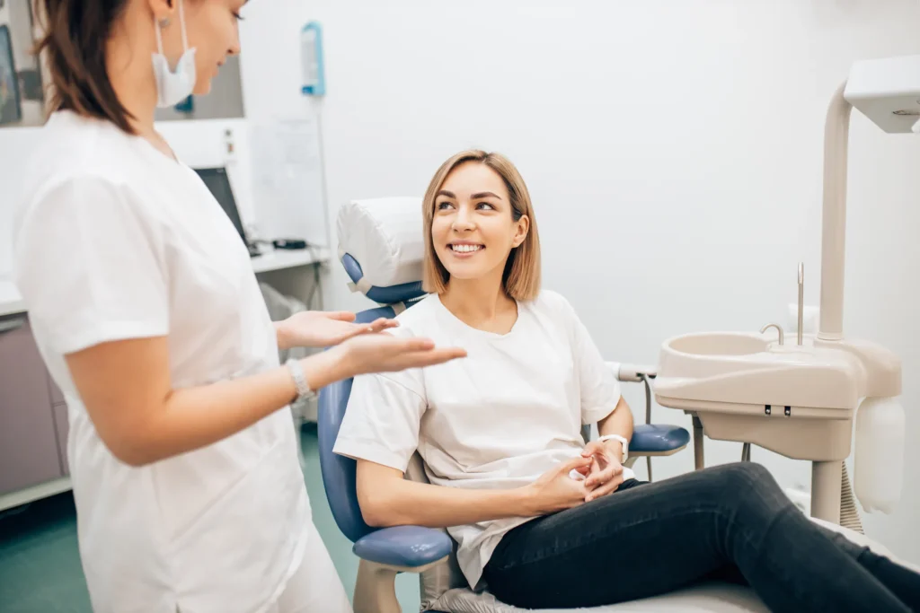 A clinician talking with a smiling patient seated in the treatment room