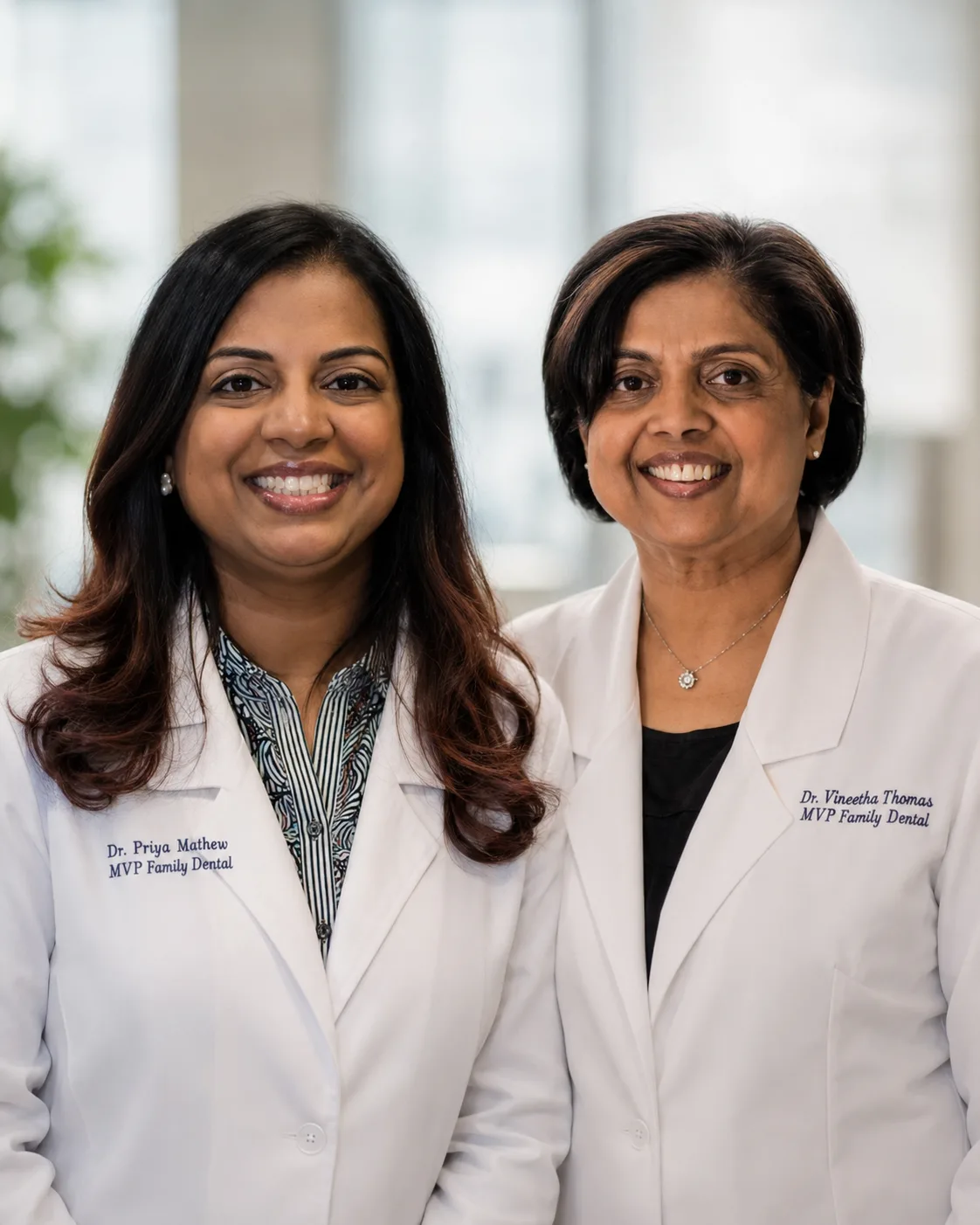 Dr. Priya Mathew and Dr. Vineetha Thomas together in white MVP Family Dental coats