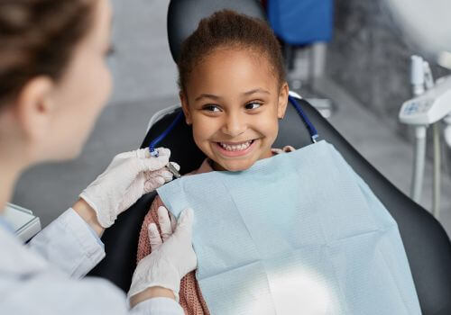 Young girl smiling in the dental chair while a hygienist works