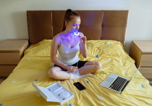 A woman using an LED at-home teeth whitening kit