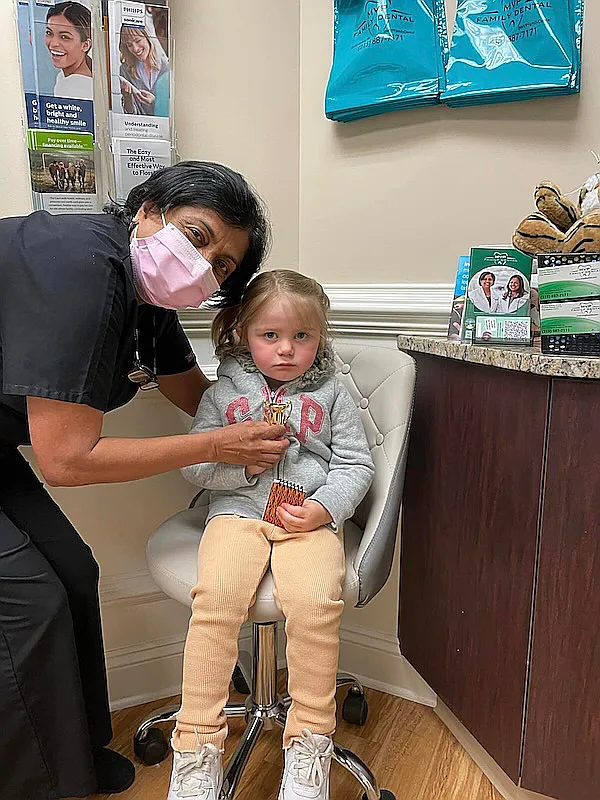 A masked team member holding a small child at the front desk