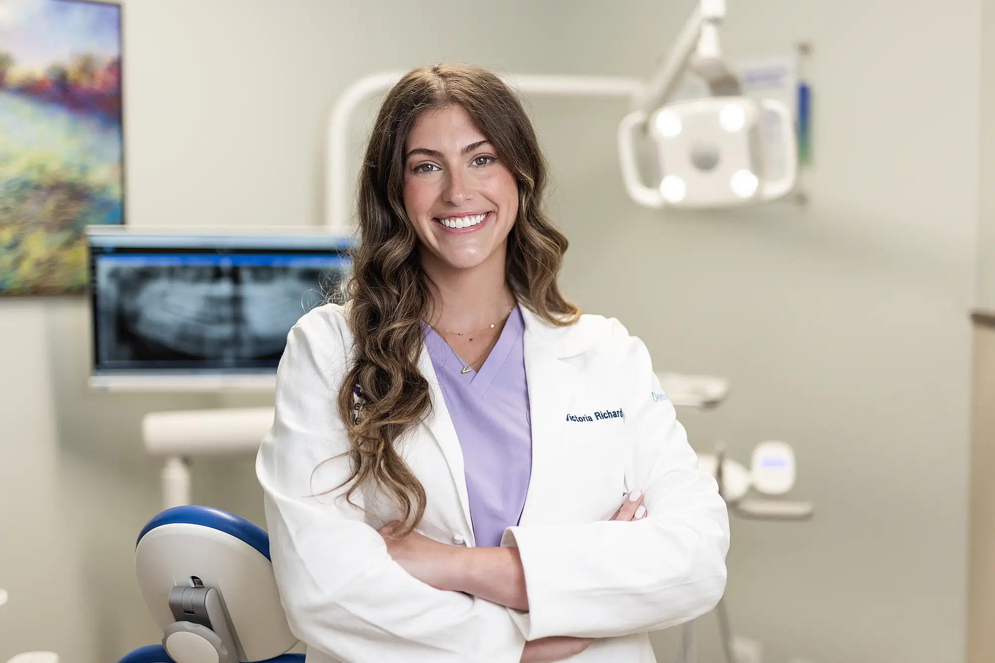 Dr. Victoria Richardson standing beside a dental chair with her arms folded
