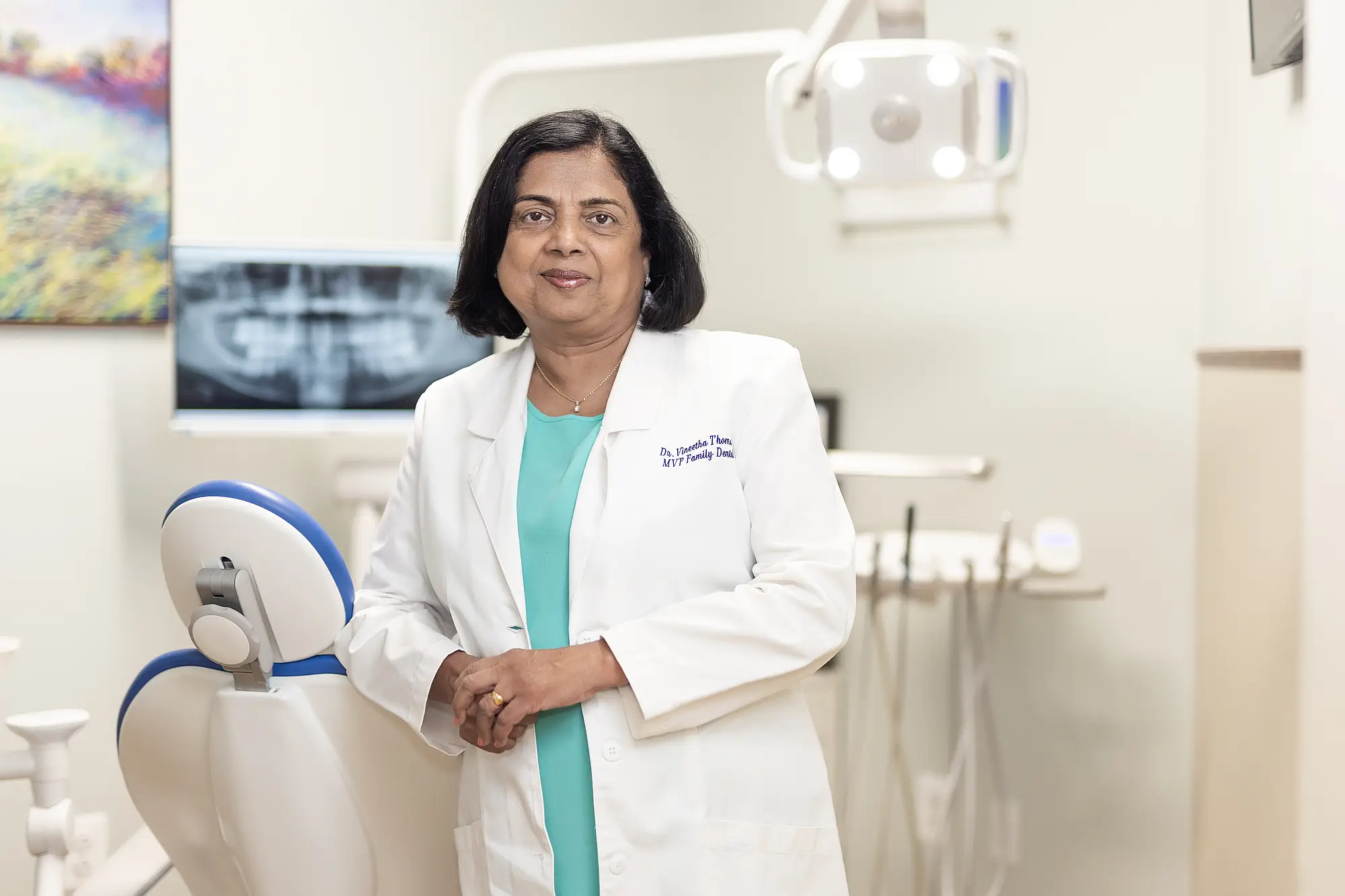 Dr. Vineetha Thomas beside a dental chair in a treatment room