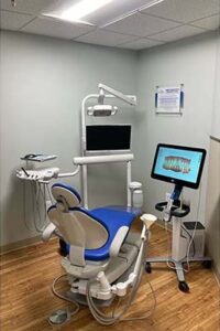 Operatory with a blue dental chair and two chairside screens