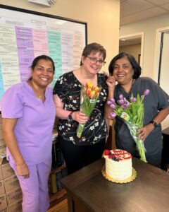 Three team members with flowers and a birthday cake