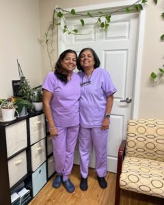 Two team members in scrubs by the treatment room door