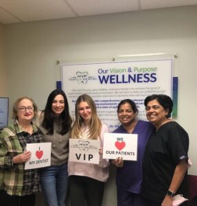 Team members holding signs in front of the practice vision and purpose board