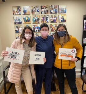 Three team members holding handwritten signs about the practice