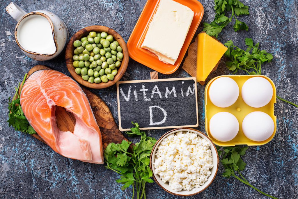 Foods rich in vitamin D including salmon, eggs, cheese and milk around a vitamin D label