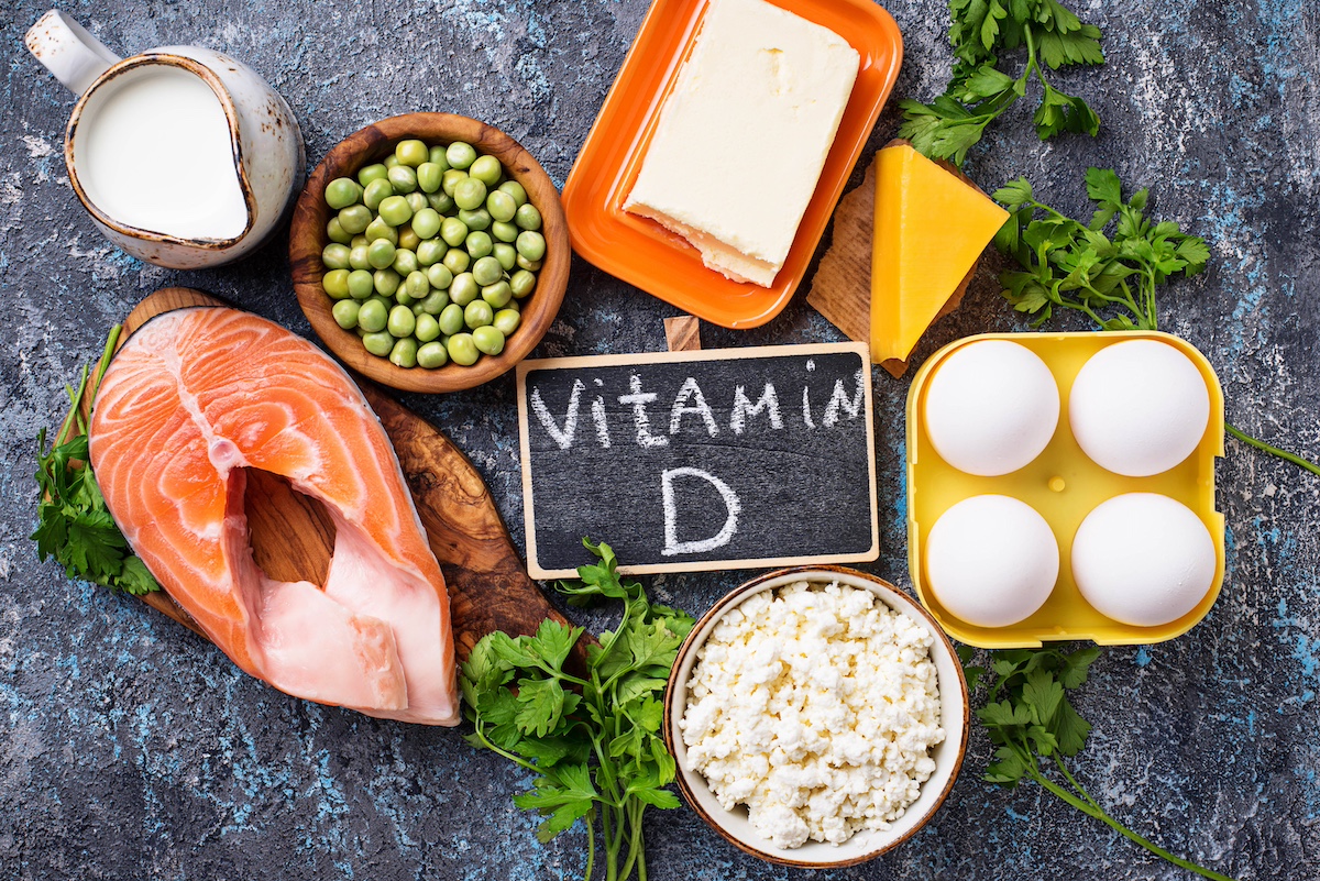 Foods rich in vitamin D including salmon, eggs, cheese and milk around a vitamin D label