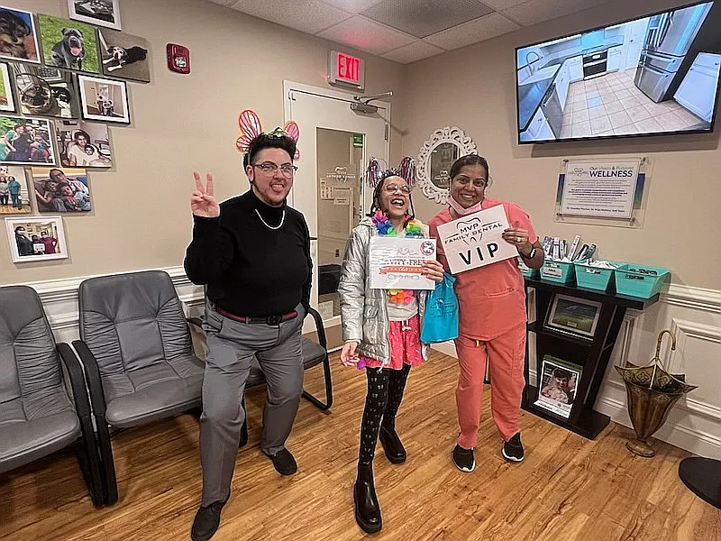 Three team members in costume holding a VIP sign in the waiting room