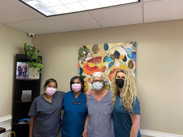 MVP Family Dental team members posing with a patient in front of colorful floral artwork