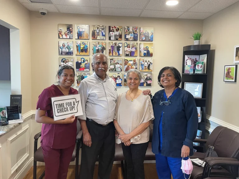 Dental team with two patients holding a Time for a Check-Up sign in the waiting room