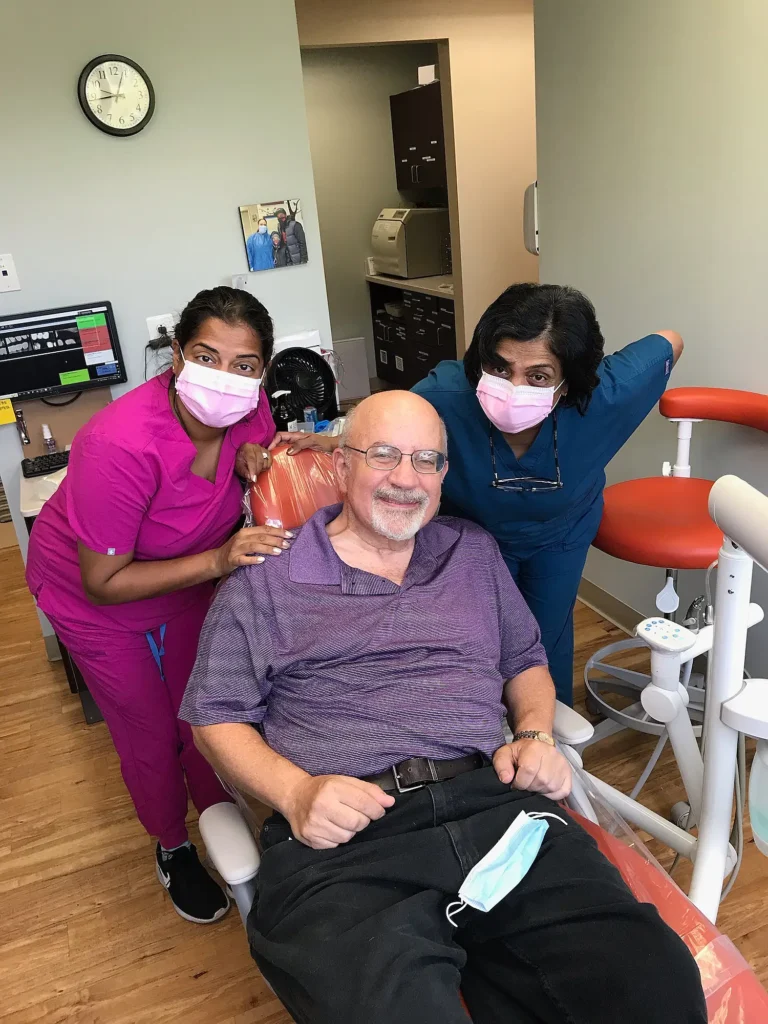 Smiling patient in the dental chair with two MVP Family Dental team members