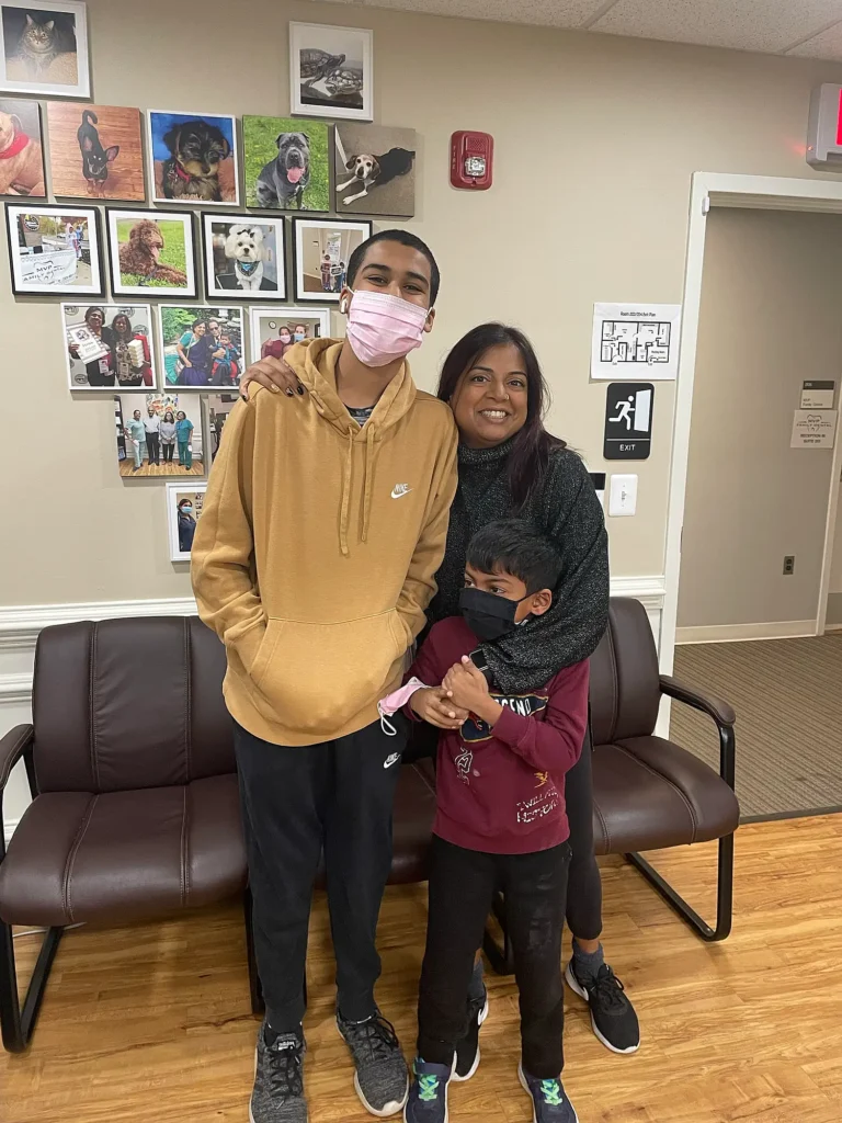Family with a teen and young child smiling together in the MVP Family Dental waiting room