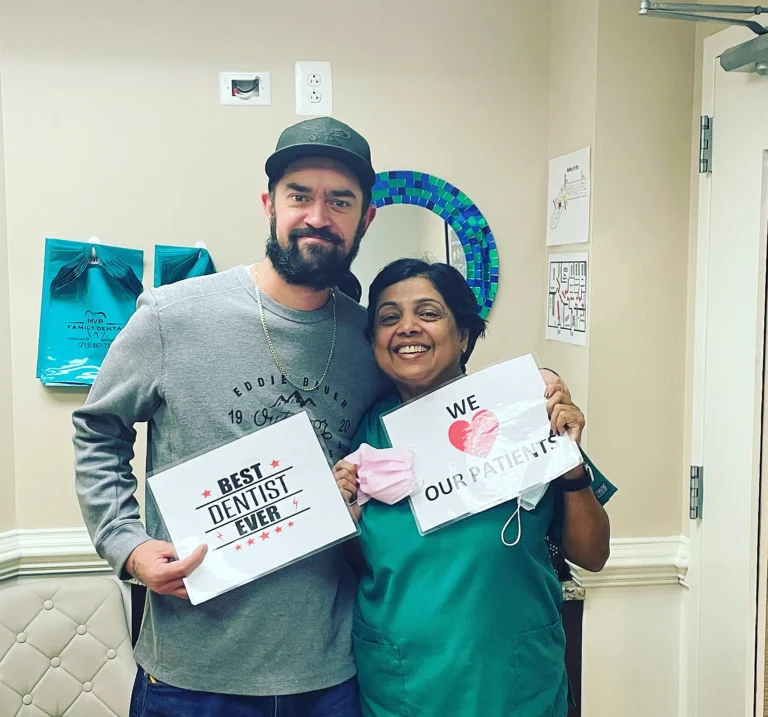 Happy patient and dental team member holding Best Dentist Ever and We Love Our Patients signs
