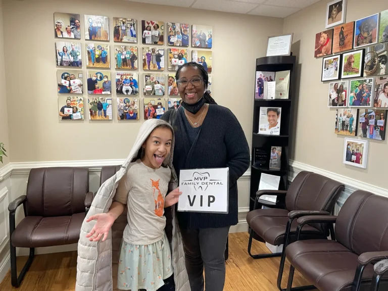 Young patient holding a VIP sign with a parent in the MVP Family Dental waiting room