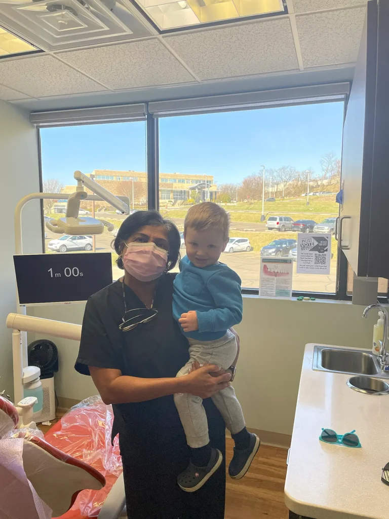 Dental team member holding a toddler in a bright treatment room at MVP Family Dental
