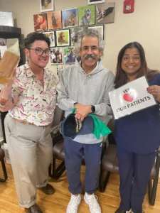 Patients with a dental team member holding a We Love Our Patients sign in the waiting room