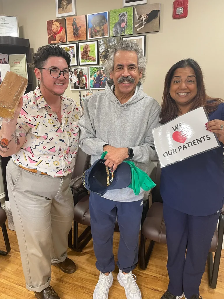 Patients with a dental team member holding a We Love Our Patients sign in the waiting room