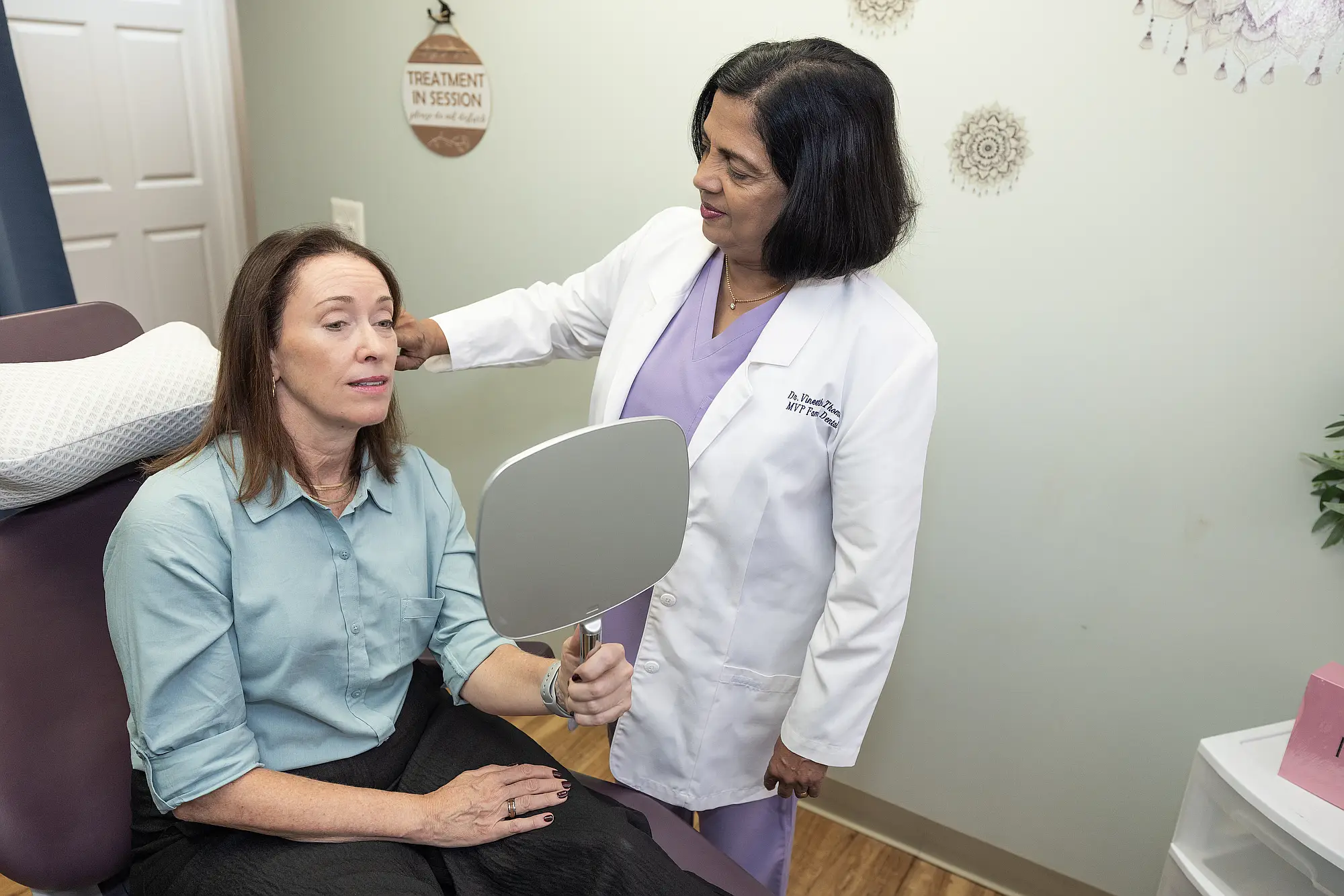 Dr. Priya Mathew talking with a patient holding a hand mirror