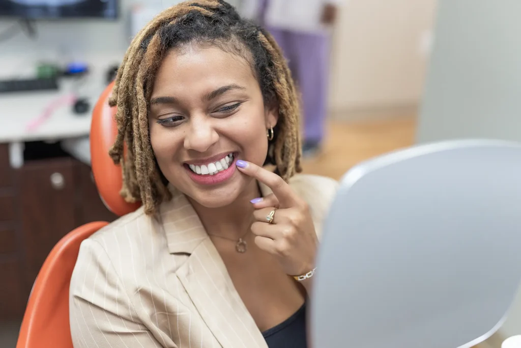 Patient pointing at her smile in a dental chair