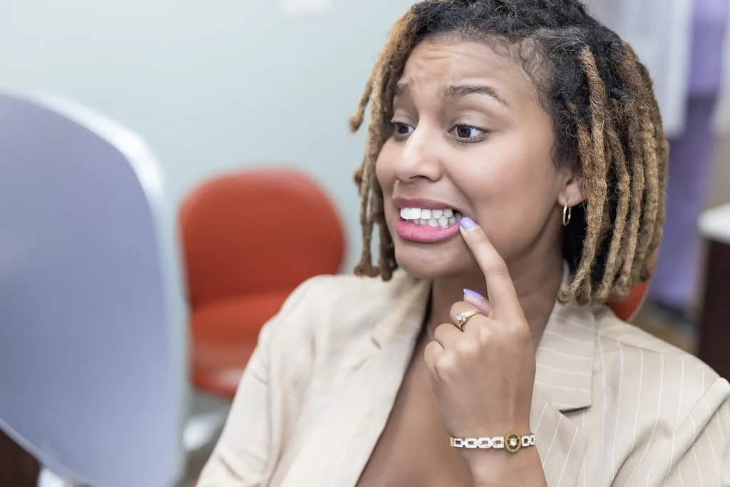 Patient pointing at her teeth in a dental chair