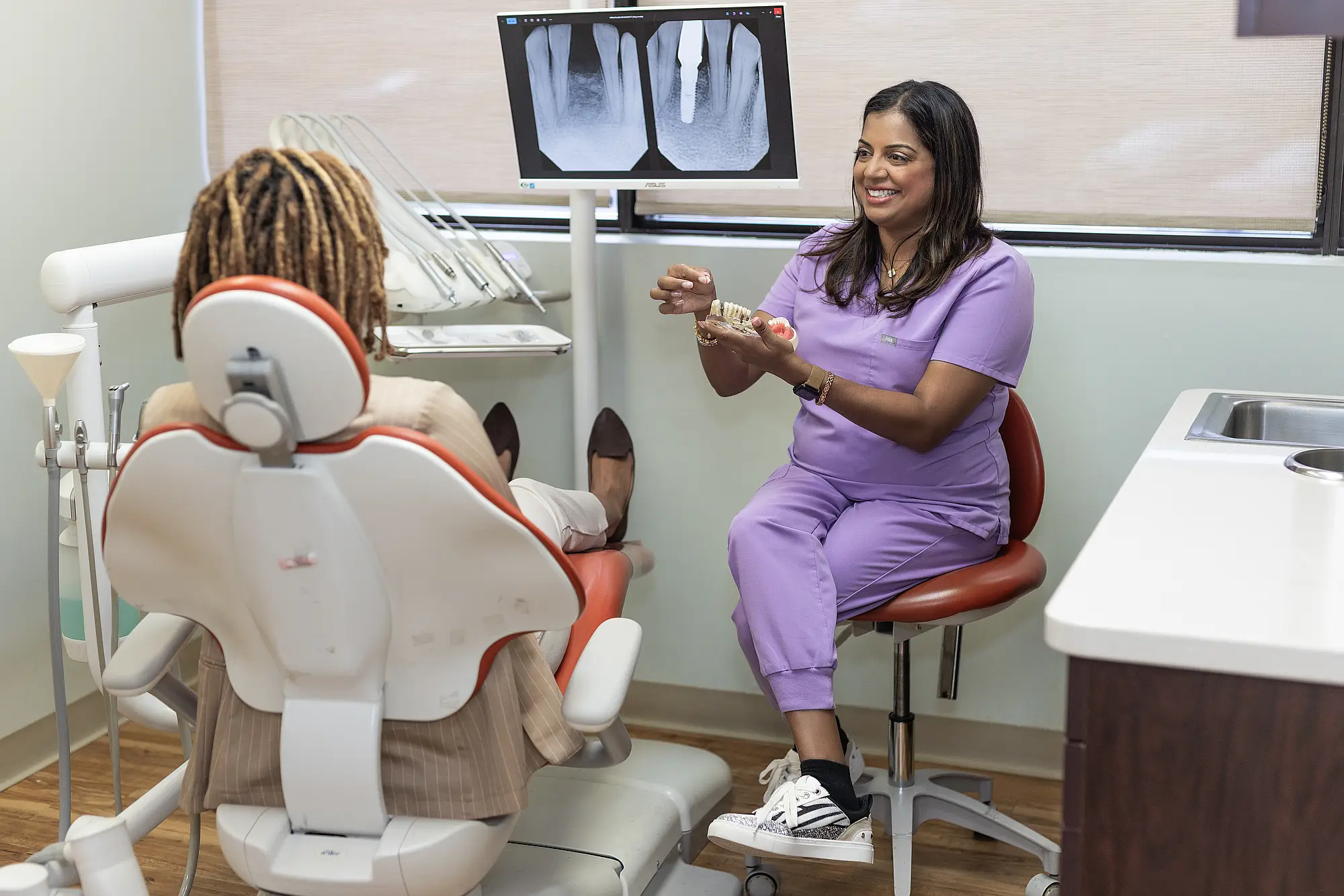 Dr. Priya Mathew reviewing dental X-rays with a patient