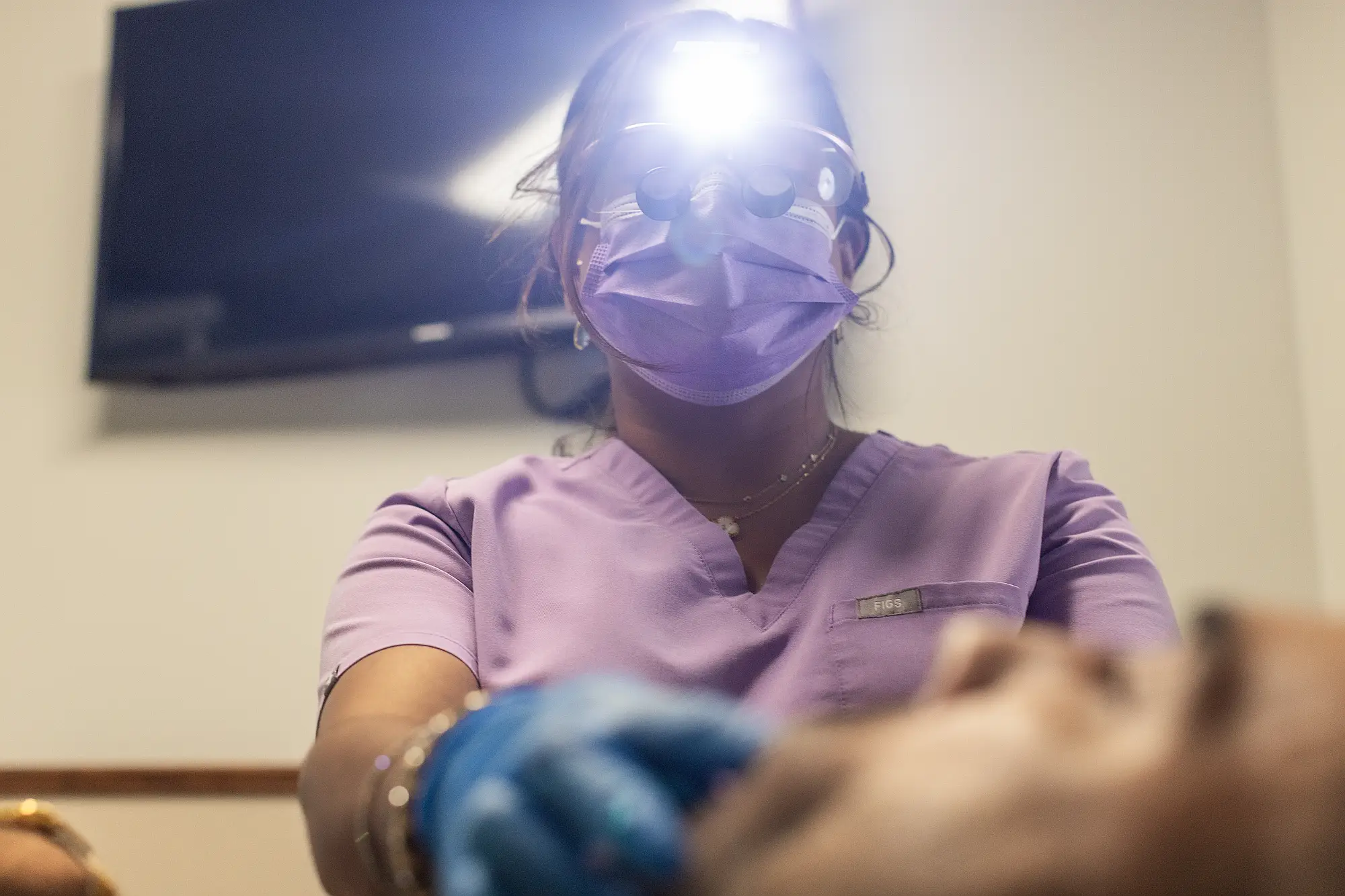 Hygienist working on a patient under a headlamp