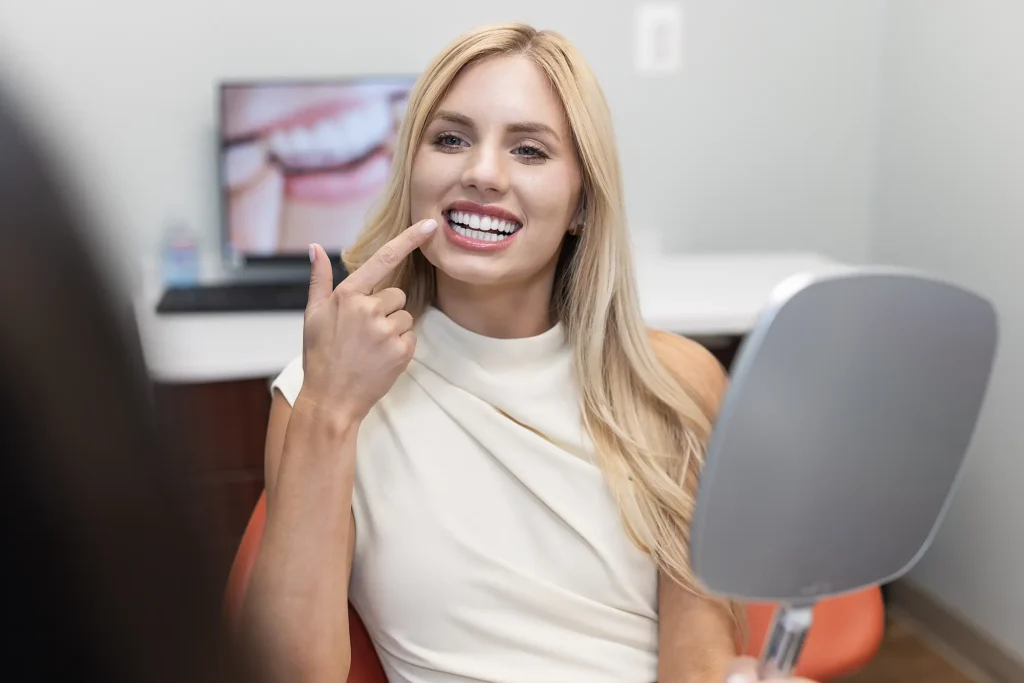Patient pointing at her smile in a dental chair