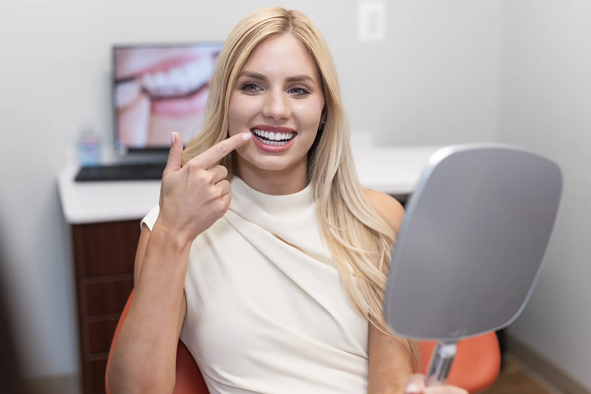 Patient pointing at her front teeth while holding a mirror