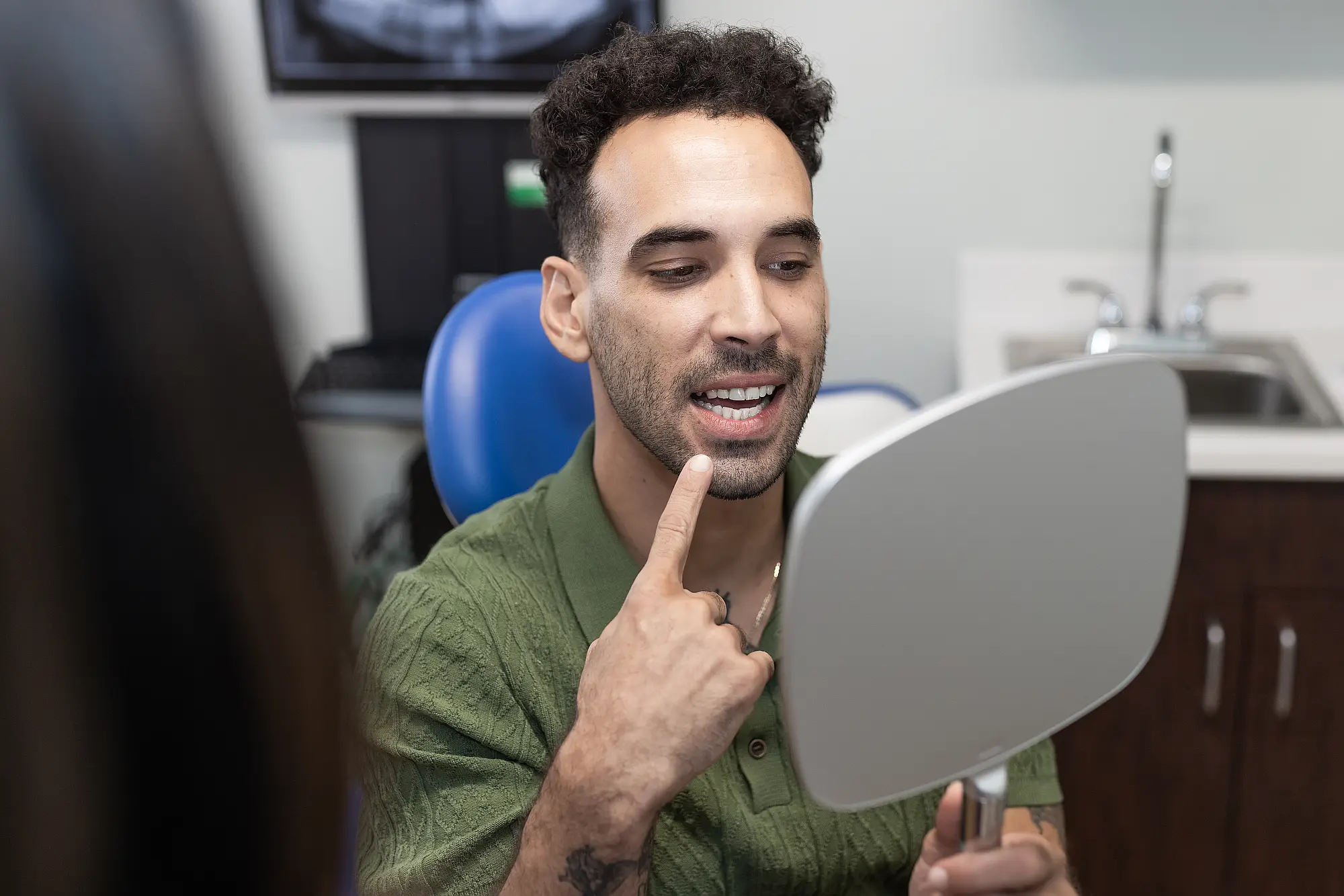 Patient looking at his new smile in a hand mirror