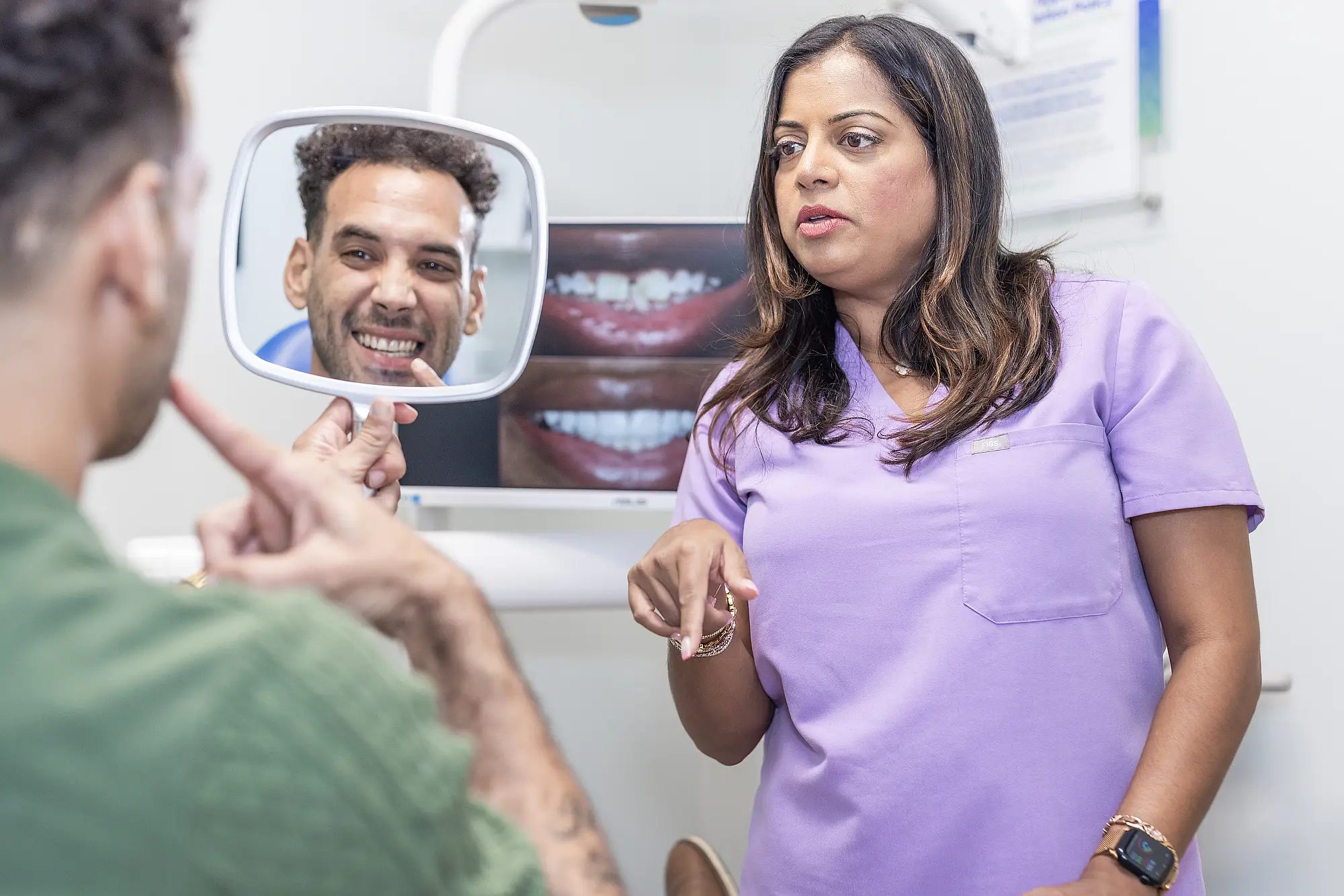 Dr. Priya Mathew showing a patient his smile in a mirror
