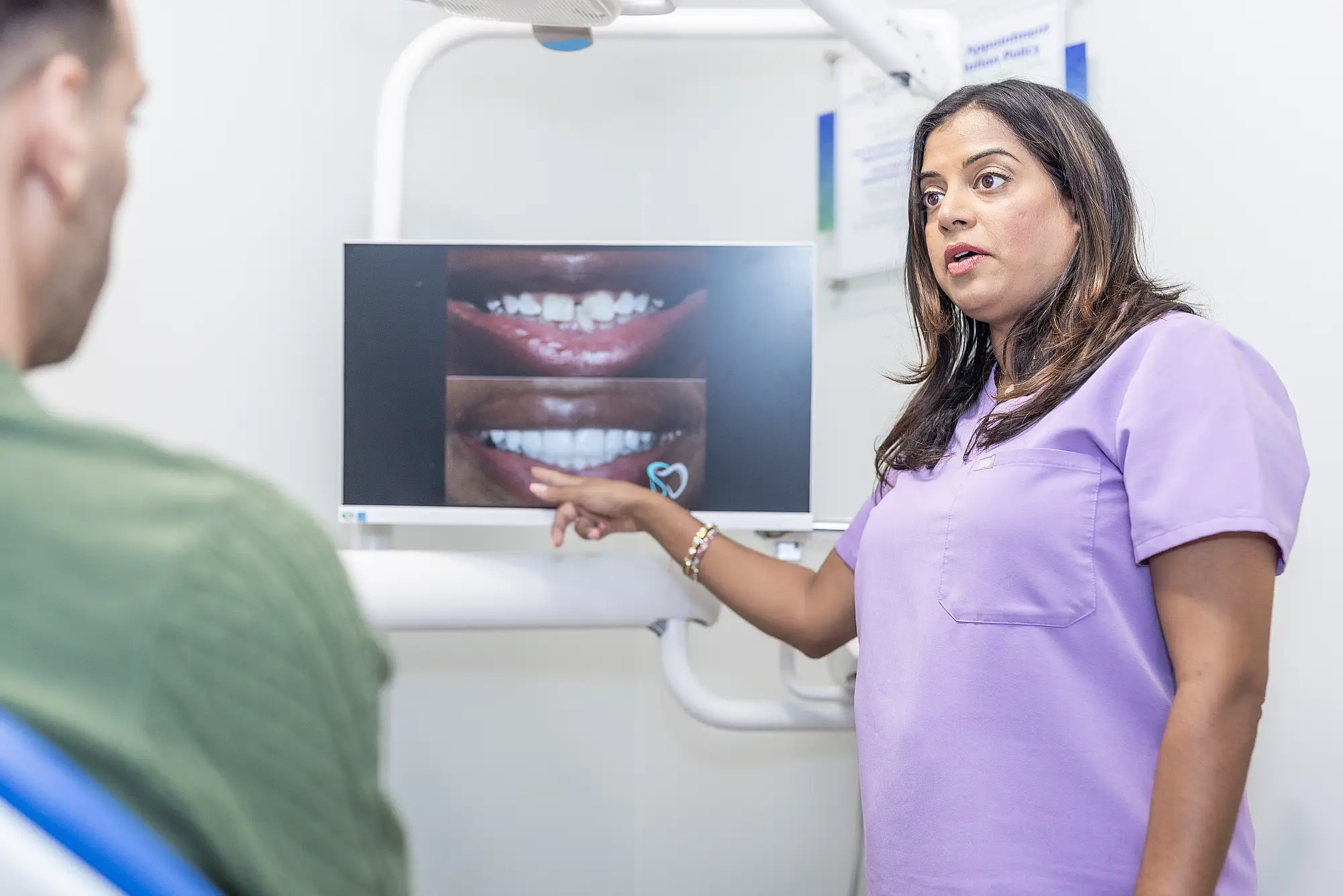 Dr. Priya Mathew pointing at before and after smile images