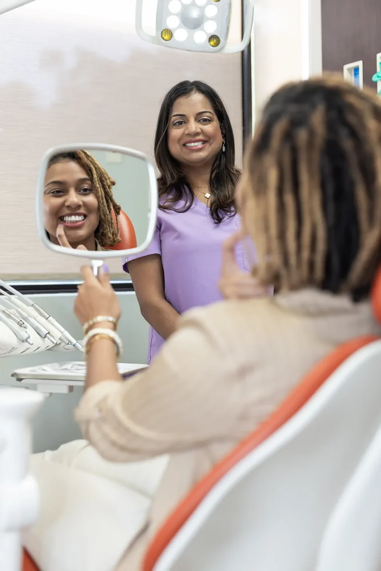 Patient viewing her smile in a mirror with Dr. Priya Mathew