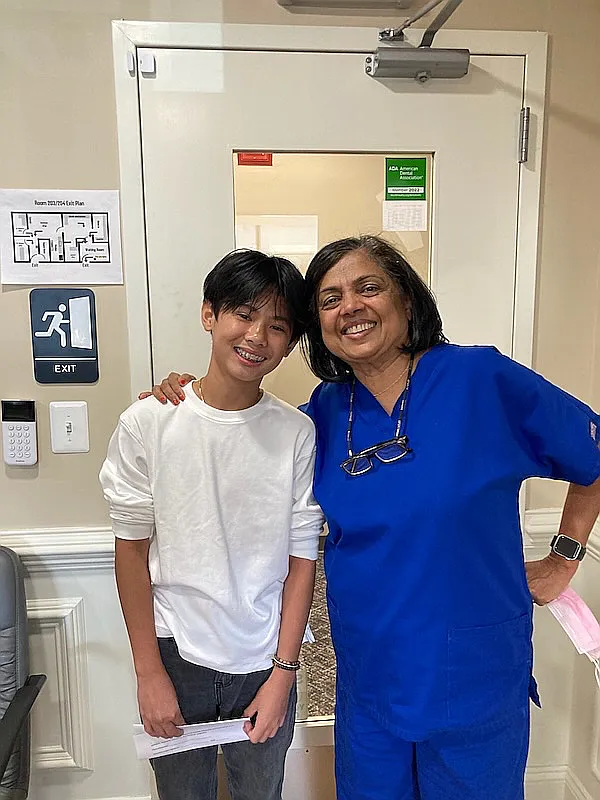 A teenage patient standing with a team member by the practice door